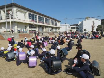 運動場で地区別に登校班で並ぶ児童たちの様子