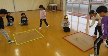 遊戯室で園児たちがこま回し大会をしている様子