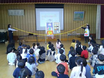 遊戯室で講師に腸の長さを見せてもらっている園児たちの様子