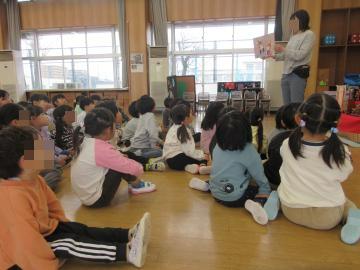 床に座って紙芝居を見ている子供たちの様子