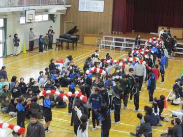 体育館で6年生が花のアーチをくぐって退場しているところ