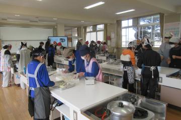 調理室で、5年生が調理実習で棒状の白玉粉を小さく丸めている様子