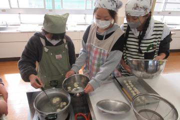 調理室で、浮き上がった白玉を穴じゃくしですくい上げ、冷水に入れている児童たちの様子
