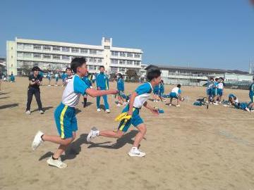 グラウンドで生徒がたすきをわたす様子