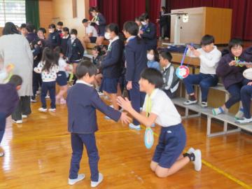 体育館で、1年生からプレゼントのメダルを受け取る6年生の様子