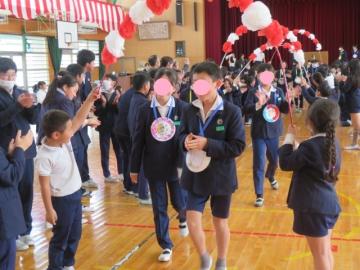 体育館で、みんなに送られ、笑顔で花道を退場する6年生の様子