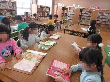 図書室の絵本を椅子に座って読んでいる子供たちの写真