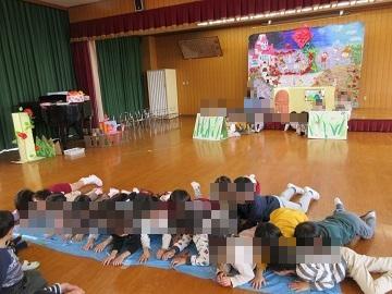 遊戯室で川にみたてたシートの上に寝転ぶ全園児