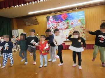 遊戯室で子供数名が片足をあげたり手をあげたりして踊っている写真