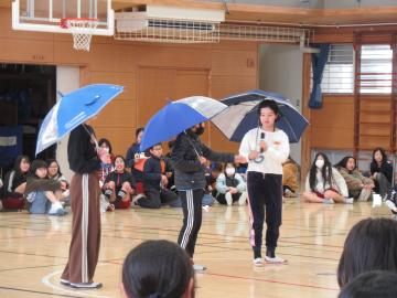 在校生が傘をさして出し物をしている写真