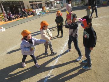 園庭で3歳児たちが4歳児が演じる鬼たちに豆をまいている様子