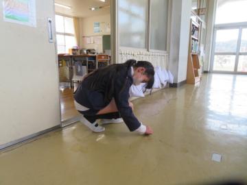 ろうかの汚れをそうじする6年生