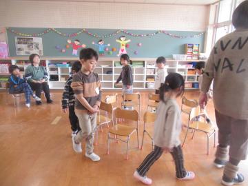 室内で園児たちがお別れ会で椅子取りゲームをしている様子