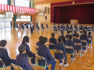 体育館で卒業式予行をする生徒達に話す教師のようす