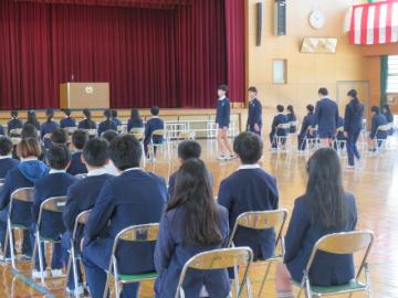 体育館で6年生の卒業式入場を座って見守る5年生