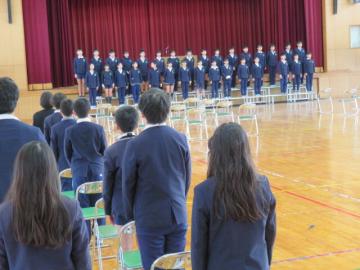 体育館で6年生の歌を聞く5年生のようす