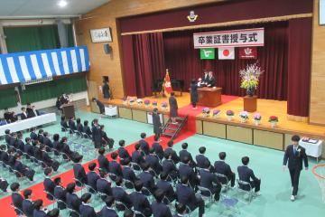 体育館で校長先生から卒業証書を受け取っている9年生の様子