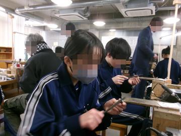 技術室でシルバーリングの作成のために鉄の棒を手に持っている生徒たち