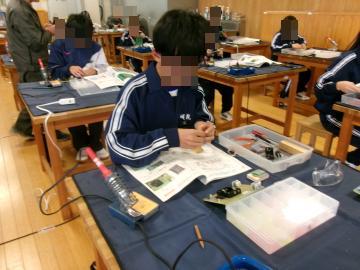 技術室で、各自のテーブルで教科書を見ながらロボットカーを組み立てている生徒達