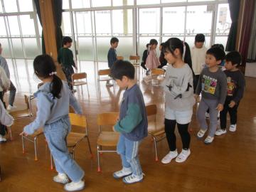 円く並べた椅子の周りを歩く子供たち