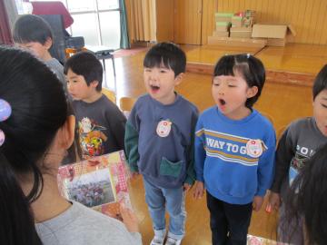 プレゼントの写真を持つ子供と、感謝の言葉を言う子供たち