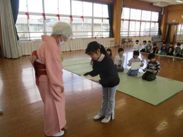 教室でお茶の講師から証書を受け取って礼をする子供
