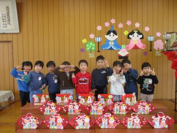 並べた手作りのひな人形の後ろで並んでポーズをする子供たち