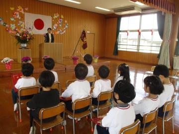 遊戯室で並べた椅子に座って園長からお祝いの言葉をもらう子供たち