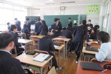 9年生が最後の学活で配布物を受け取っている様子