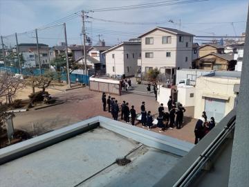 正門で卒業生を迎える在校生と教師の様子