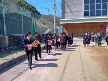 在校生・職員に見送られながら運動場を歩く卒業生たち