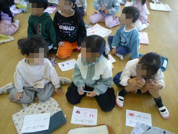 遊戯室の床に座ってビンゴゲームをしている子供たちの様子
