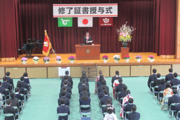 校長先生がステージ上から6年生にメッセージを伝えている様子