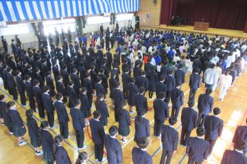 体育館での終業式で児童と生徒が校歌を歌っている様子