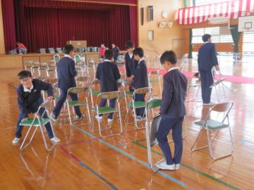 体育館に卒業式の座席を並べる5年生