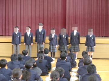 体育館の壇上に整列し、キャリア体験学習の実行委員が話をしている様子