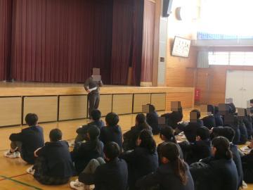 体育館の壇上前で学年主任の教員が話をしている様子