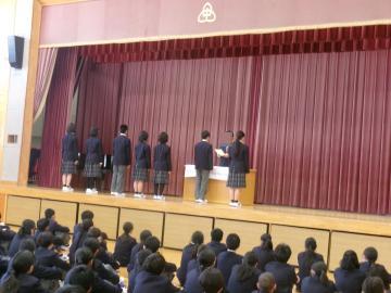 体育館の壇上で整列し、任命式に参加する生徒たちの様子