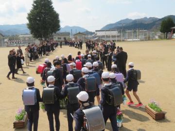 運動場の花道を保護者と5年生に見守られながら進む6年生