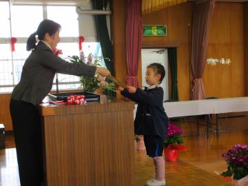 遊戯室で、4歳児が園長先生から証書を受け取っている様子
