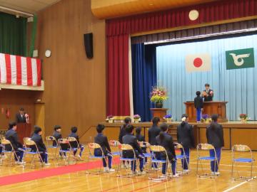 修了式で代表の児童が全校生の前で修了証を校長先生から受け取っている