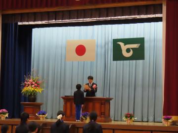 体育館の壇上で修了証を受け取る代表児童と校長先生