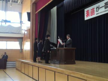 陸上競技部の生徒が、体育館の壇上で表彰を受け取る様子