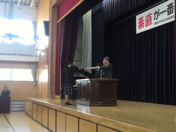 1年生の代表の生徒が体育館で修了証を受け取る様子