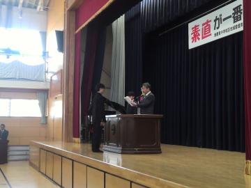 2年生の代表の生徒が体育館で修了証を受け取る様子