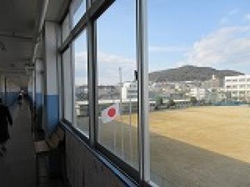 校舎内の3階から見えるグラウンドの掲揚柱の半旗の様子