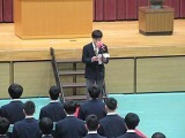 体育館の壇上前で送る言葉を読む2年生代表の生徒の様子