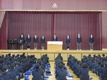 体育館の壇上に整列し、旧生徒会長が退任の挨拶をする様子