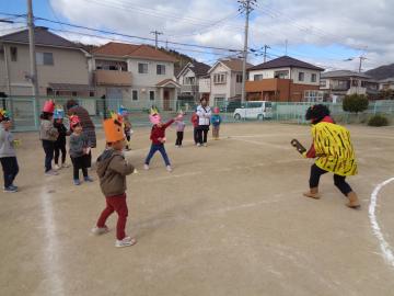 園庭に出てきた鬼に向かって園児が豆まきをしている