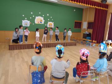 遊戯室で4歳児が司会をして5歳児にお別れ会の説明をしている